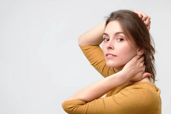 Mujer europea joven en suéter amarillo con una hermosa sonrisa en el estudio. Retrato sobre fondo gris . —  Fotos de Stock