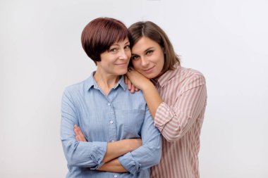 Güzel maturesenior anne ve yetişkin kızını sarılma, kameraya bakıyor ve gülümsüyor.