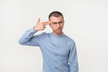 Silah jest tapınak tutarak ve surat duran gri arka plan üzerinde yorgun ya da bıkkın İspanyol adam.