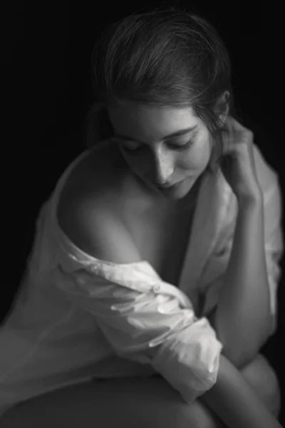 Sinnliches Porträt einer schönen, glücklichen jungen Frau, die auf einem Bett liegt und ein weißes Hemd trägt. — Stockfoto