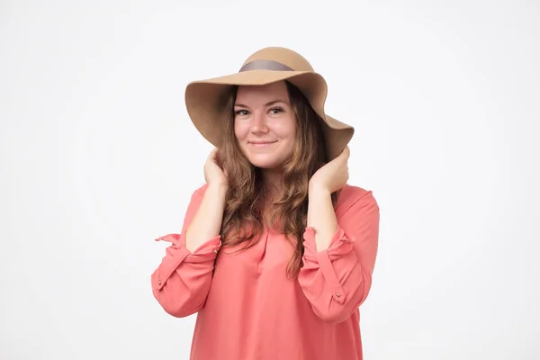 Sonriente chica gorda caucásica en un sombrero con maquillaje natural y camisa roja mirando a la cámara. Ella está disfrutando de la vida . — Foto de Stock