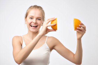 Güzel sarışın genç kadın turuncu beyaz arka plan karşı dururken gülümseyerek başını yakınındaki bir holding beyaz gömlekli. Sağlıklı beslenme ve meyve yeme kavramı