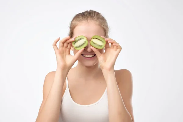 Kiwi. Healthy fruit funny woman holding kiwi fruit for her eyes. Confident facial emotion