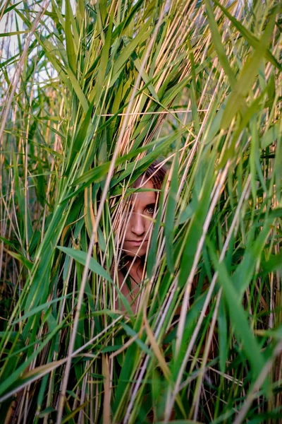 young european woman in the grass in summertime. She is hiding in high grass