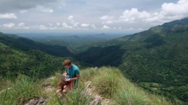 tepenin üstünde laptop ile mutlu bir adam