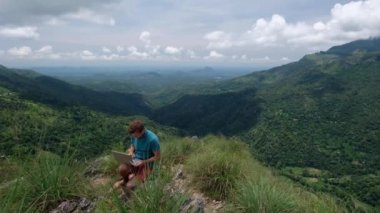 tepenin üstünde laptop ile mutlu bir adam