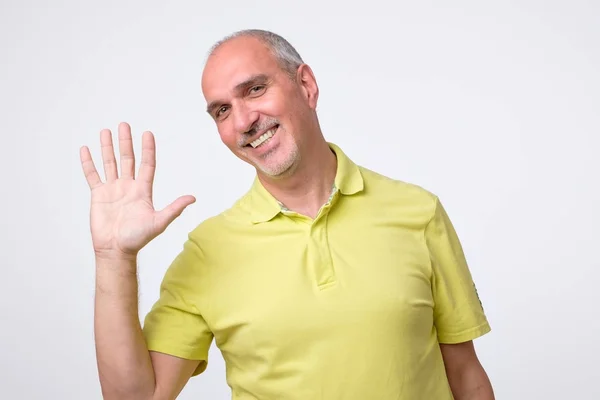 Freundlich aussehender attraktiver europäischer Mann, der in Hallo-Geste auf die Hand verzichtet und fröhlich lächelt. — Stockfoto