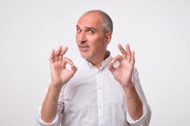 Beyaz tişörtlü yakışıklı olgun adam Ok işaret gösteren, kameraya bakıyor ve gülümsüyor