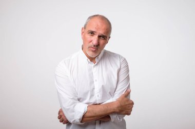 yüzünde ciddi ve üzücü ifade ile Beyaz tişörtlü Olgun yakışıklı adam portresi.