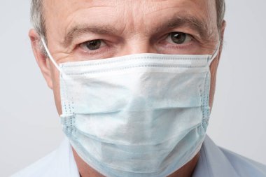 Özel doktor maskeli ciddi adam portresi kapatın. Ciddi bakıyor. Olgun deneyimli doktor.