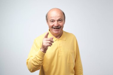 Çekici komuta sizde forefingers sana ile işaret portresi, gülümsüyor geniş diş ile gri duvar karşı izole rahat sarı tişört giymiş. Olumlu duygular