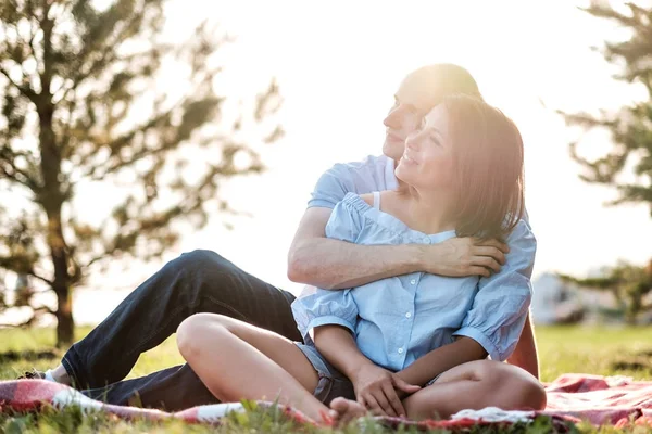 年轻的情侣在户外坐在草地上 拥抱着 看着远方 未来和关系概念 — 图库照片