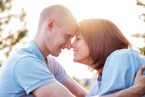 Young loving couple outdoors sitting on grass, hugging and looking on each other with love. Future and relationships concept