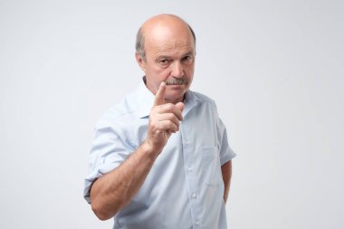 Uyarı parmak ve mavi tişört gömlek karşı açık gri renkli olan ciddi üst düzey adam portresi. Benim tavsiye kavramı dinlesen iyi edersin