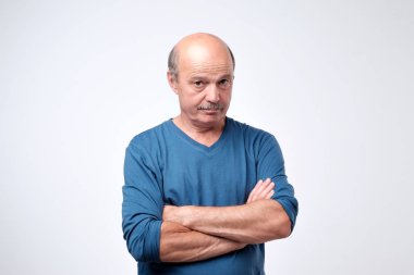Çapraz elleri olan olgun emin ciddi adam portresi.
