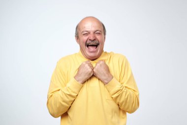 Sarı tshirt beyaz arka plan üzerinde kameraya bakarak gülen bıyıklı Olgun yetişkin adam. Bir kaç şaka yaşındasın ama altın. Olumlu duygu kavramı