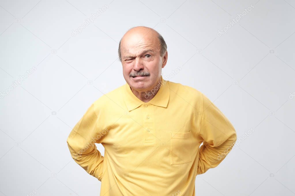 Mature man in yellow t-shirt with nervous crisis isolated on white background