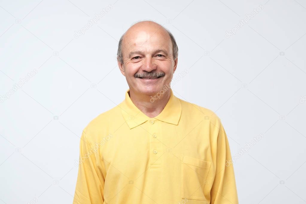 Portrait of mature european man looking at camera and smiling. Positive facial emotion