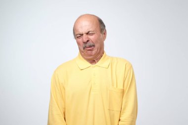 Shocked mature man looking at something unpleasant and bad, isolated on gray background. Negative emotion concept. Fail in a relationship or at work clipart