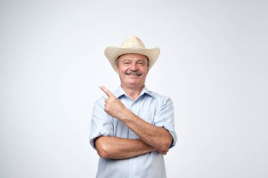 Senin burada reklam. Stüdyo portre mavi gömlek ve kovboy şapkası kopya alanı duvarda gösterilen yakışıklı komuta sizde. Mutlu yaşlı Amerikalı bir parmak ilginç bir teklif gösterilen