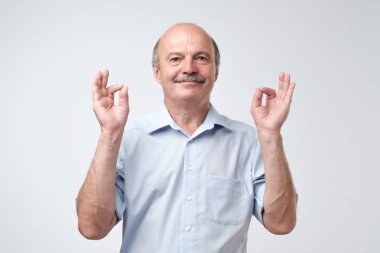 Mavi gömlek çalışır zor çalışma günü, hayalleri, sonra dinlenmek için konsantre olgun adam parmaklarını birlikte tutar. Meditasyon ve kavram rahatla.