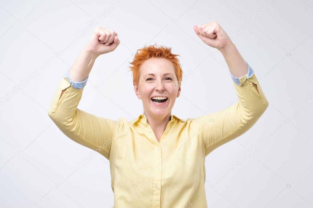 happy caucasian woman with red hair exults pumping fists ecstatic celebrates success. I have done it Wow concept