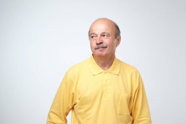 Olgun yaşlı çekici adam kuşkucu göz, şaşkınlık, yükseltir kaş ile sarı gömlekli bazı şüphelerim var, merakla bir yana, beyaz arka plan üzerinde izole görünüyor