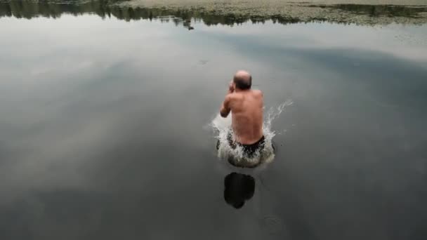 Caucasiano homem maduro pulando de cais de madeira no lago . — Vídeo de Stock