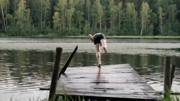 Caucásico maduro hombre saltando de madera muelle en el lago . — Vídeo de stock