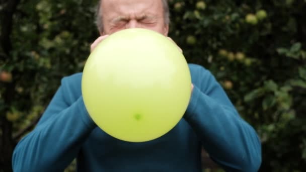 Ώριμος άνδρας φυσώντας ένα μπαλόνι — Αρχείο Βίντεο