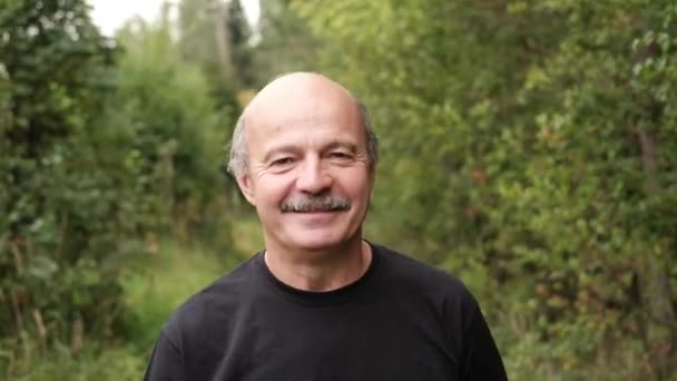 Lycklig senior kaukasiska man går utanför i park av träd. — Stockvideo