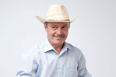 Kovboy şapkasını ayarlama ve bir kenara duran gri arka planı arıyorum olgun adam