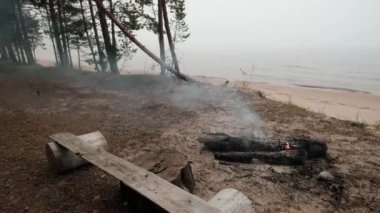 Göl su yakınında kumlu plaj küçük ateşin ortasına. Birisi yangını söndürmek için unuttum.