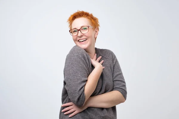 Καυκάσιος αρκετά ώριμη γυναίκα με σύντομο hairstyle κόκκινο σε απλό pulover είναι ντροπαλός για να ακούσω μια φιλοφρόνηση. — Φωτογραφία Αρχείου