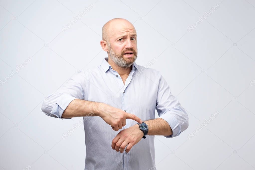 Mature european businessman impatiently pointing to his watch. Why are you late concept. I am waiting here for hours.