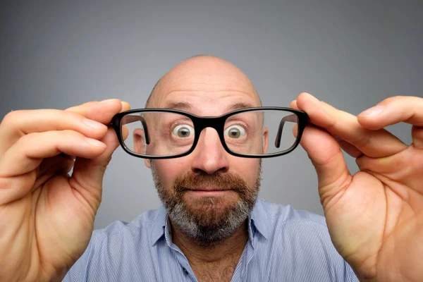 Funny european man looking through glasses. Have problems with eyesight. His eyes are looking very small