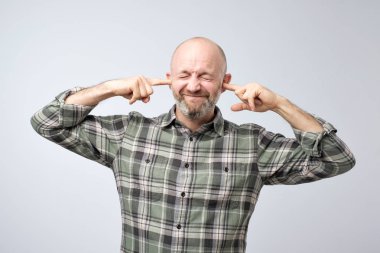 Rahatsız olgun adam parmak ile kulakları tıkalı. Bu dedikodu duymak istemiyorum