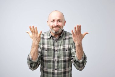 Heyecanlı over-emotive olgun adam gri arka plan üzerinde eller fotoğraf makinesi ve savunarak veya gösterilen pişmanlık doğru çekerek stüdyo çekim