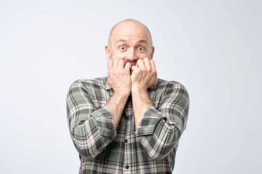 O korkuyor ya da endişeli biri onun parmak tırnak ısırma Olgun yakışıklı erkek portre portre. Negatif insan duygu yüz ifadesi duygu