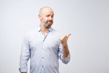 Rahat kıyafetler içinde yakışıklı sakallı adam kameraya gri arka plan üzerinde seyir söyleyerek kaçırmayın gibi bu teklif sokmadan başparmak işaret ediyor.