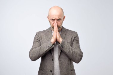 Sefil olgun adam dilencilik ifade ile rahat kıyafetli jest dua eller tutar. Lütfen bana bir iyilik yapmak.