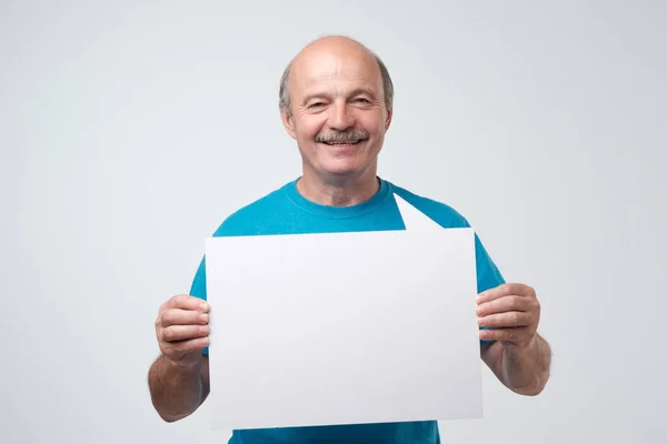 Senior hispanische Mann mit Schnurrbart hält das weiße Schild in einem Studio weißen Hintergrund — Stockfoto