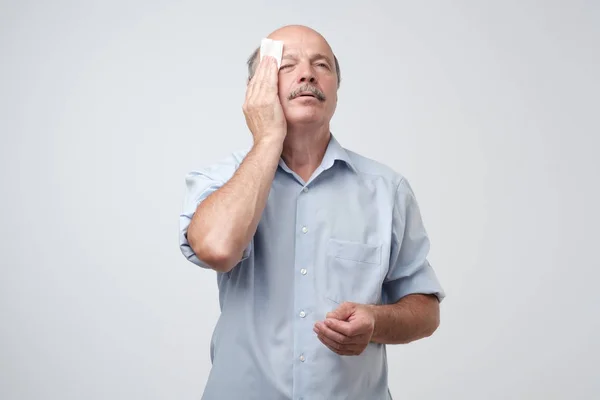 Cansado velho com bigode estressado sudorese tendo febre dor de cabeça isolada no fundo da parede cinza — Fotografia de Stock