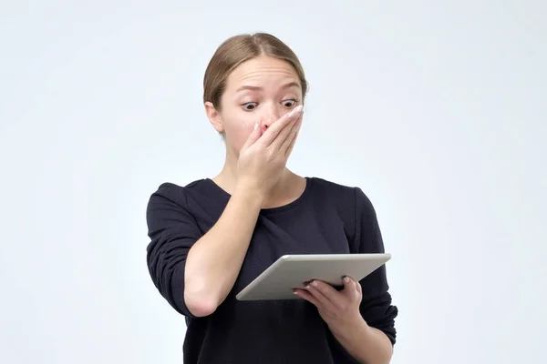 Donna scioccata guardando tablet digitale con sorpresa e shock su sfondo grigio — Foto Stock