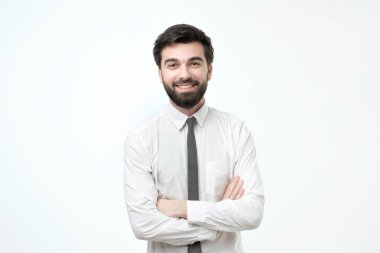 Çapraz kol ve gri arka plan üzerinde beyaz gömlek giymiş sakal İspanyol adamla gülümseyen