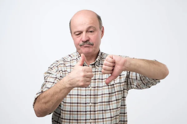 Careca sênior mostrando polegares para cima e polegares para baixo . — Fotografia de Stock