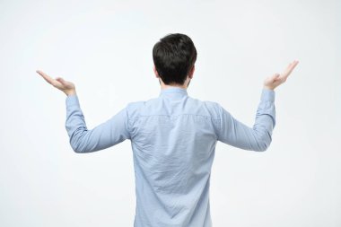 Mavi gömlek ayakta geri kamera için genç adam stüdyo çekimleri.