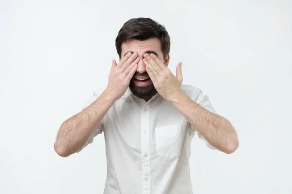Time to receive surprise. Hispanic man in white shirt covering eyes with palms and smiling — Stock Photo, Image