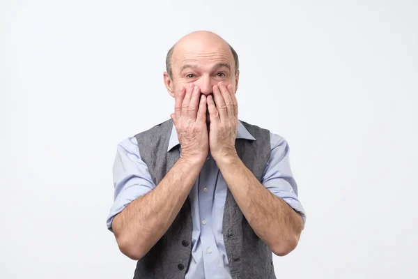 Reifer, schockierter, überraschter Mann mit Händen, die den Mund bedecken, mit weit aufgerissenen Augen voller Ungläubigkeit — Stockfoto