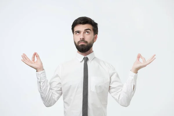 Estúdio retrato de jovem bonito macho em camisa branca, em pose de meditação, tentando relaxar — Fotografia de Stock